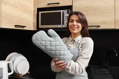 Photo of Woman wearing apron and oven glove in kitchen