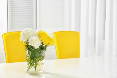 Vase with blooming flowers on table indoors