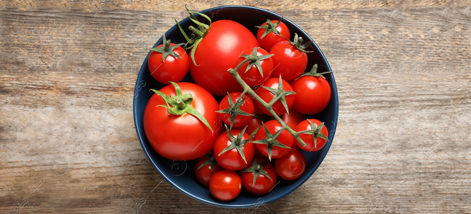 Image of Bowl with fresh tomatoes on wooden table, top view. Banner design 