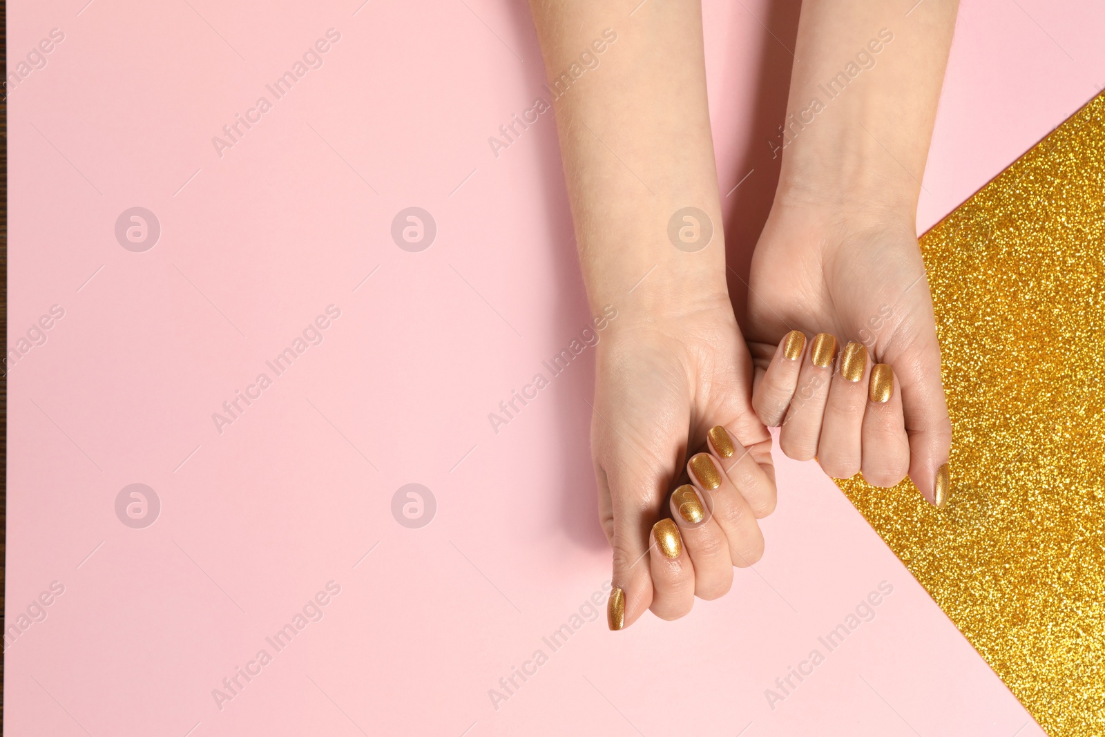 Photo of Woman showing manicured hands with golden nail polish on color background, top view. Space for text