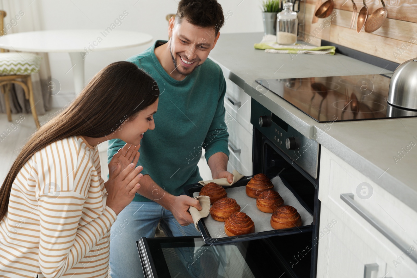 Photo of Couple baking buns in oven at home