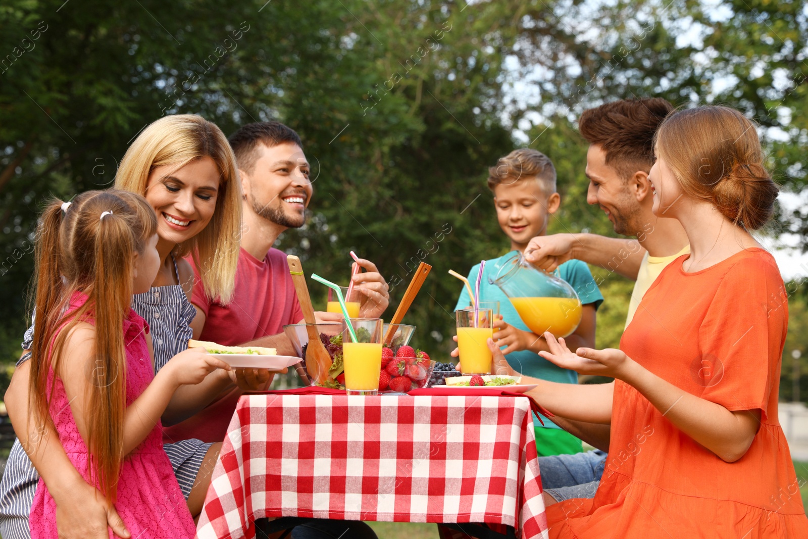 Photo of Happy families with children having picnic at table in park