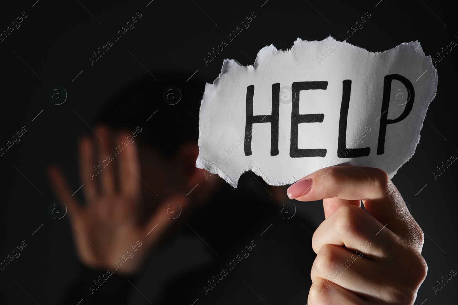 Photo of Woman holding piece of paper with word Help on black background, closeup. Domestic violence concept