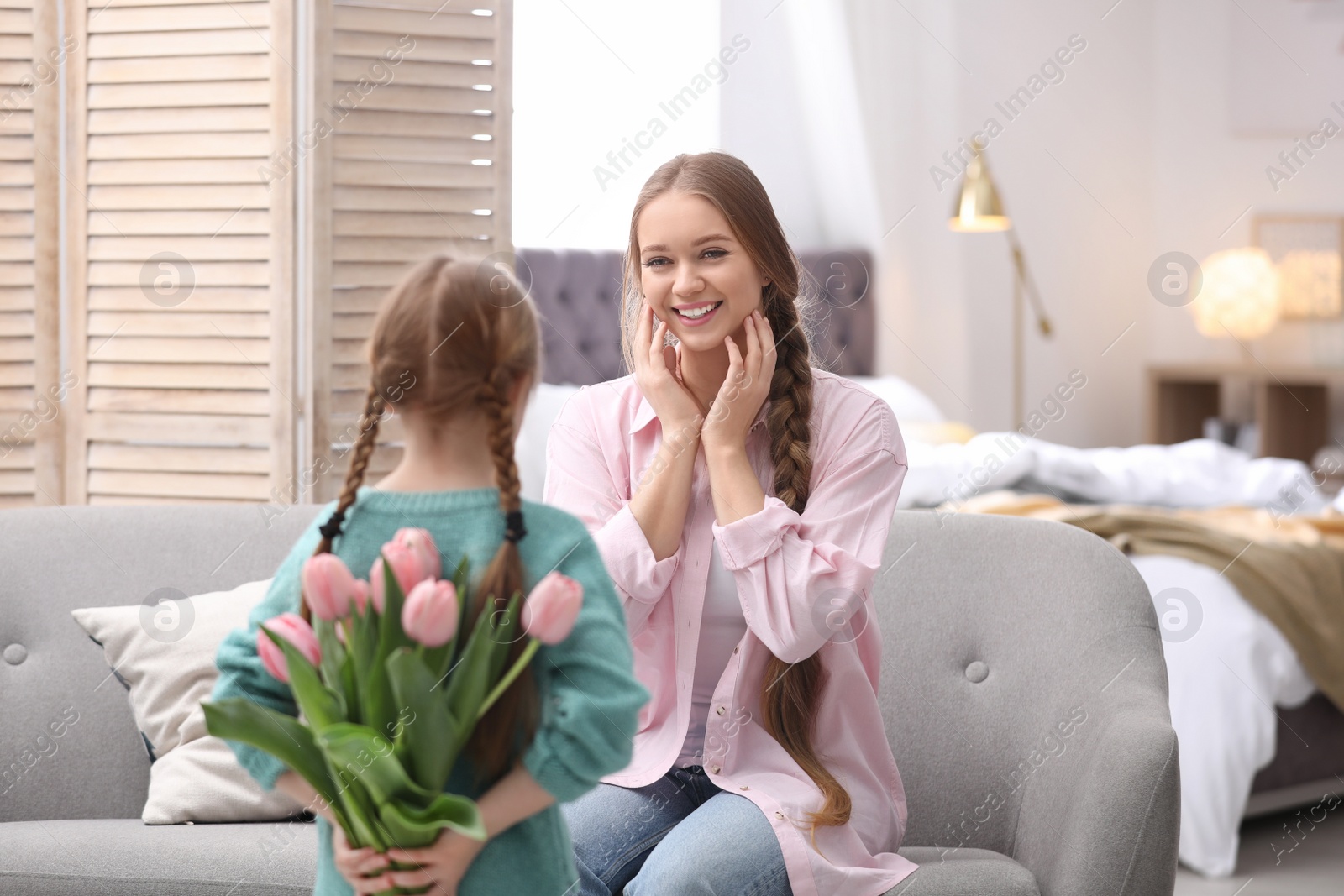 Photo of Happy mother and daughter with flower bouquet at home. International Women's Day