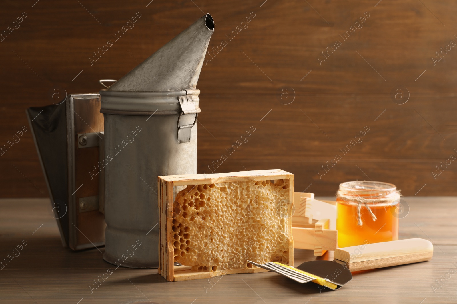 Photo of Composition with honeycomb and beekeeping tools on wooden table