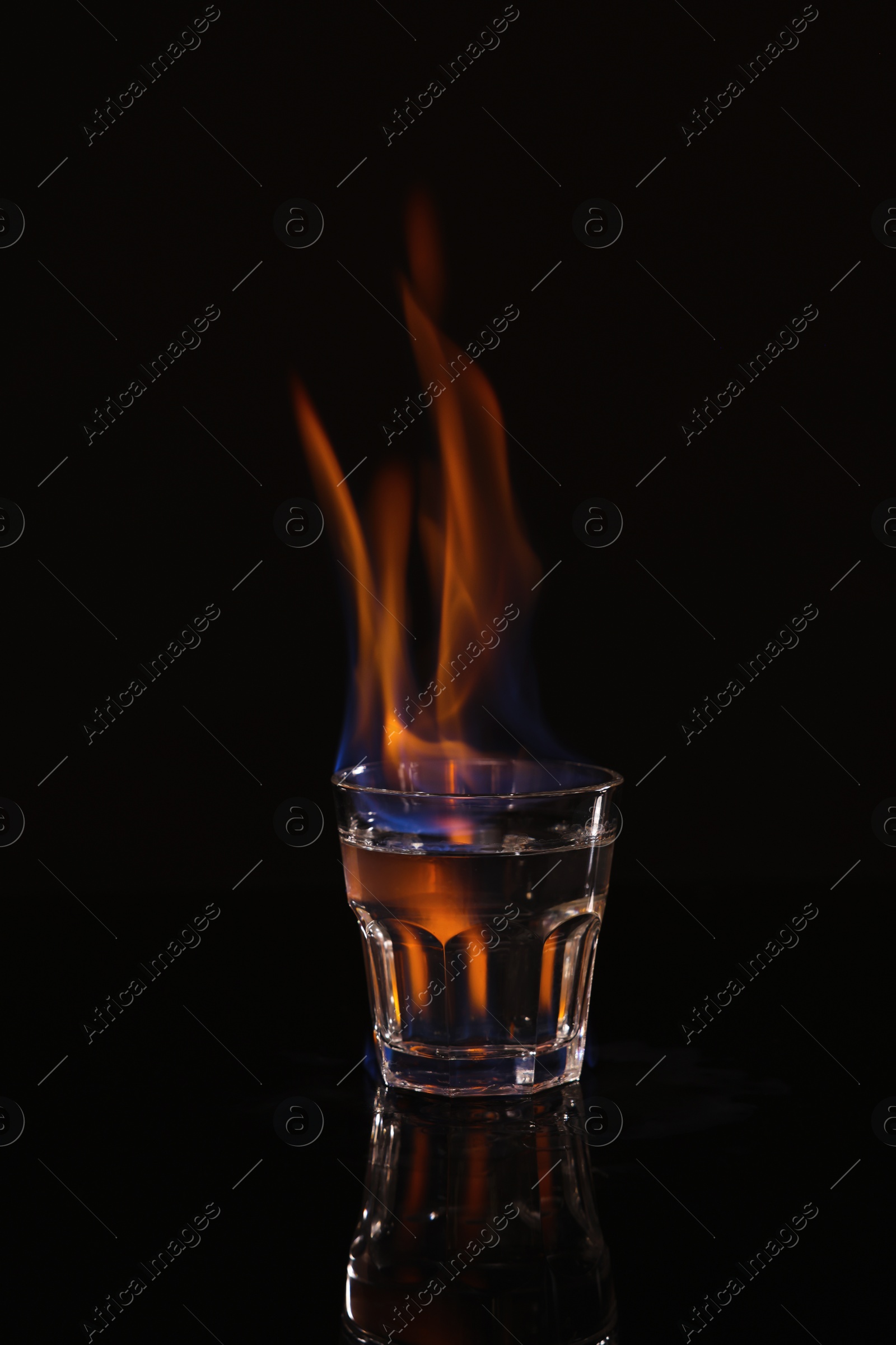 Photo of Flaming vodka in shot glass on black background