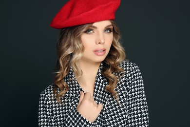 Photo of Young woman with beautiful makeup in red beret against black background