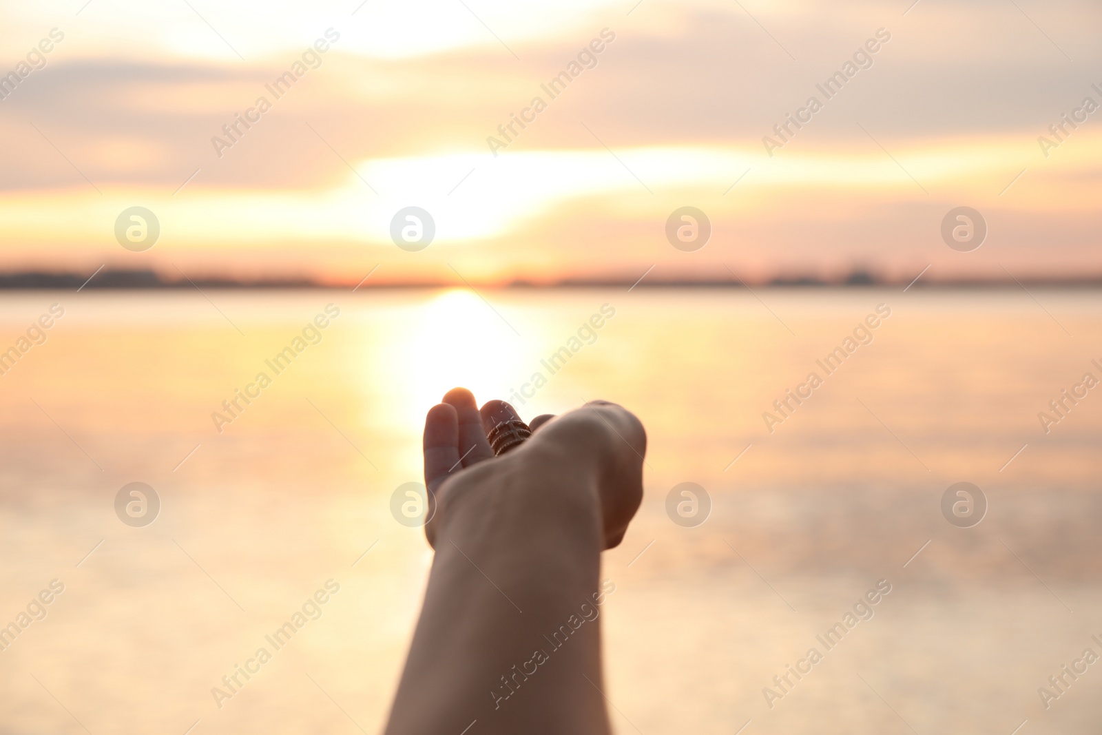 Photo of Young woman enjoying beautiful sunset near river, closeup. Nature healing power