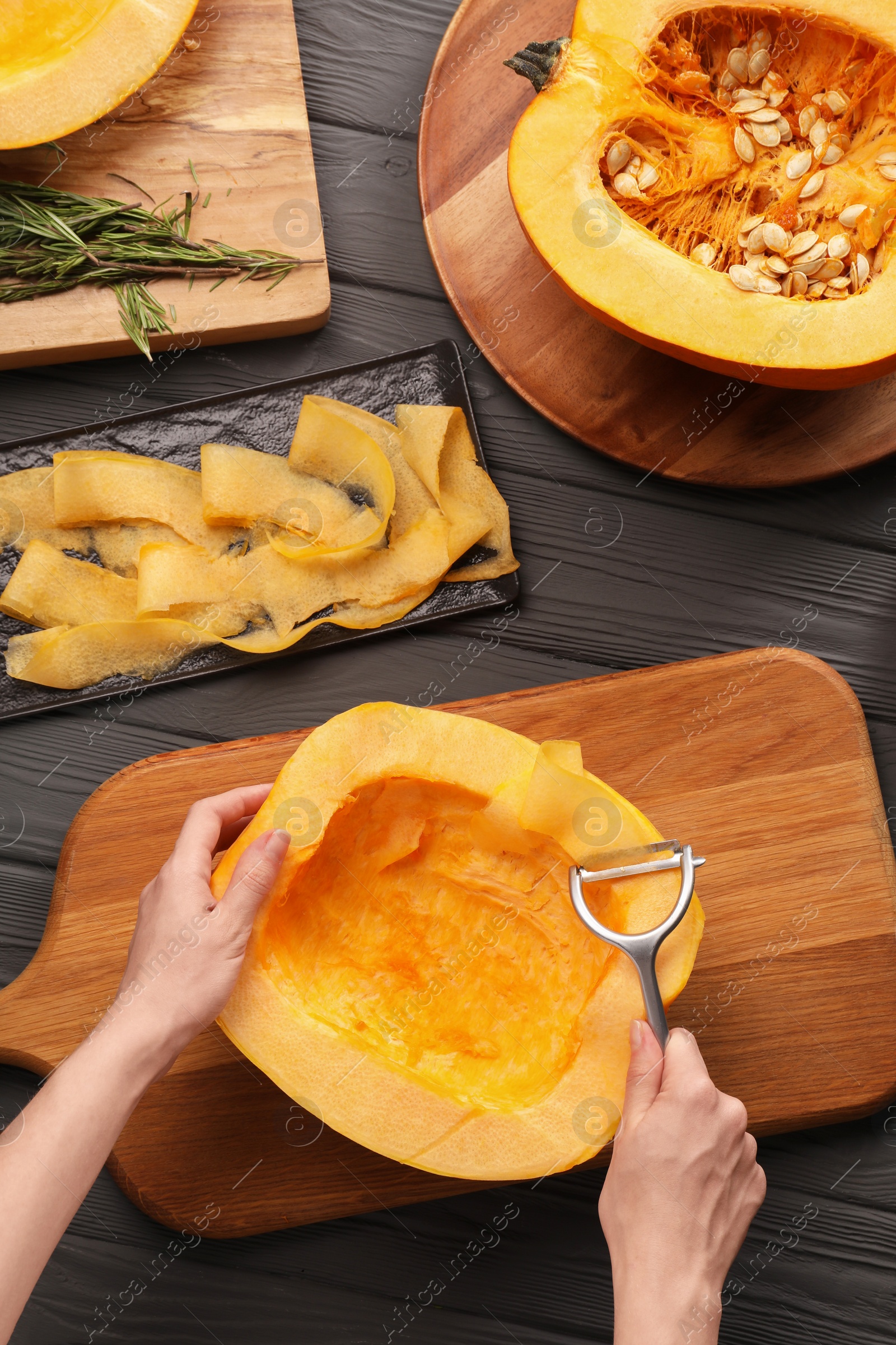 Photo of Woman slicing fresh pumpkin at grey wooden table, top view