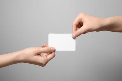 Photo of Women holding blank gift card on light grey background, closeup