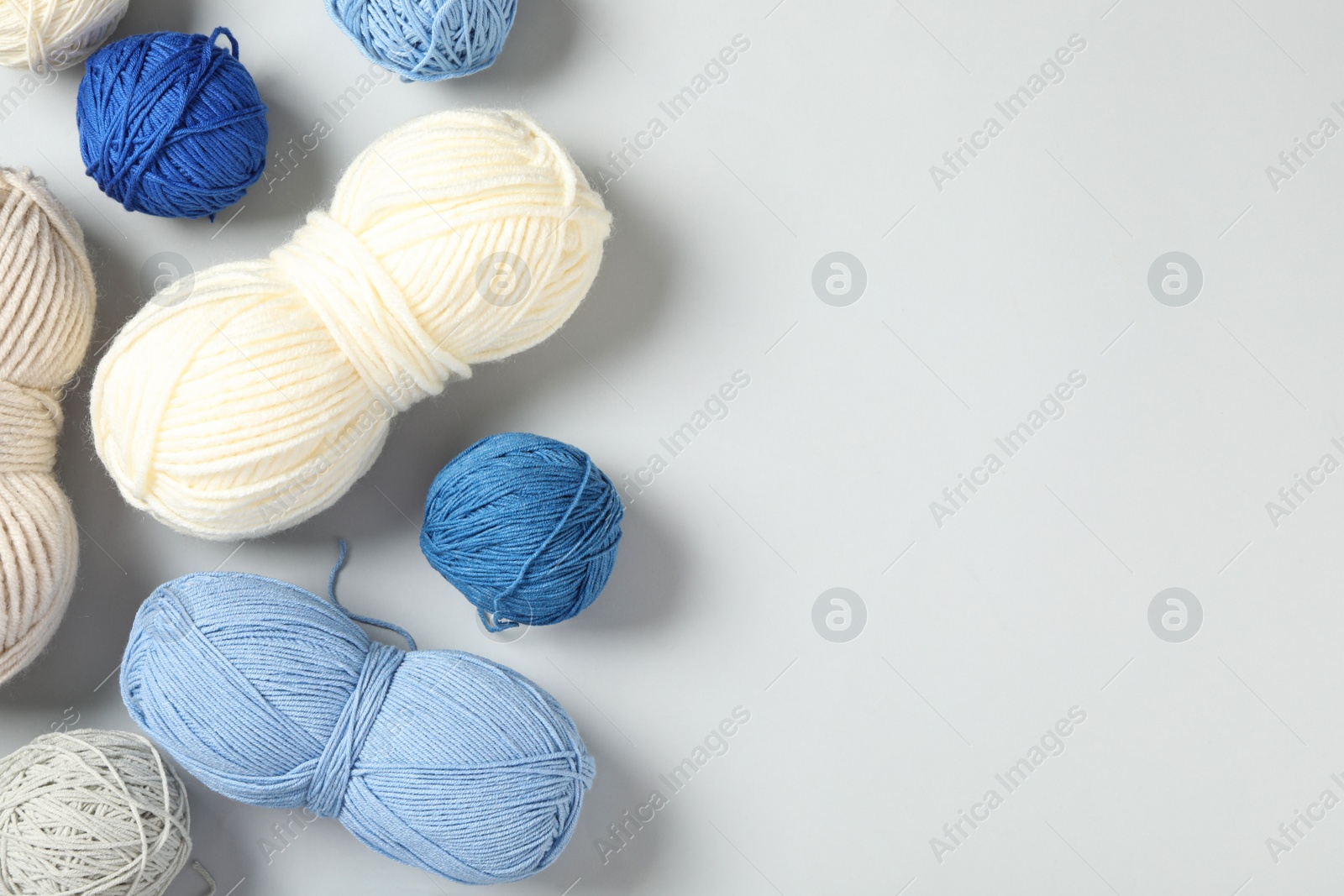 Photo of Soft colorful woolen yarns on white background, flat lay. Space for text