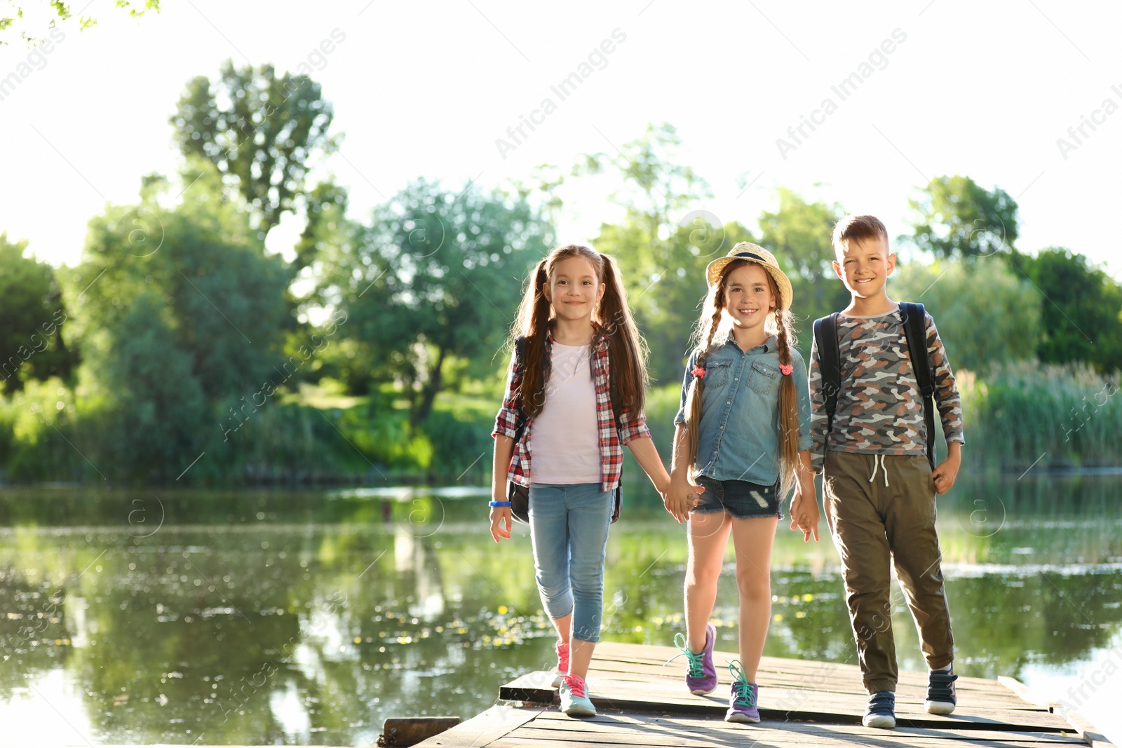 Photo of Little children on wooden pier. Summer camp