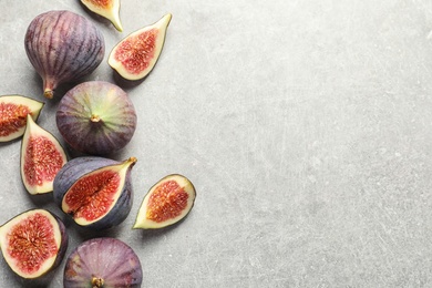 Flat lay composition with whole and cut purple figs and space for text on gray background