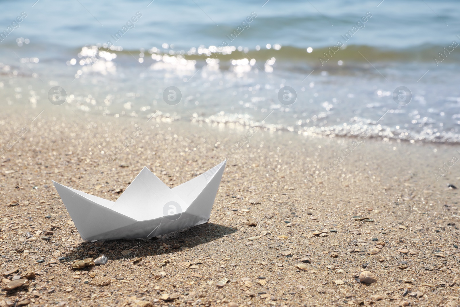 Photo of White paper boat near sea on sunny day, space for text