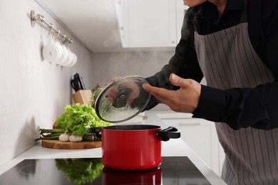 Photo of Man cooking and smelling dish on cooktop in kitchen, closeup