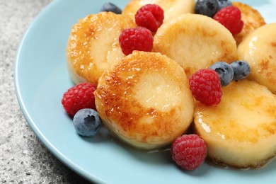 Delicious cottage cheese pancakes with fresh berries and honey on grey table, closeup