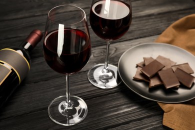 Tasty red wine and chocolate on black wooden table