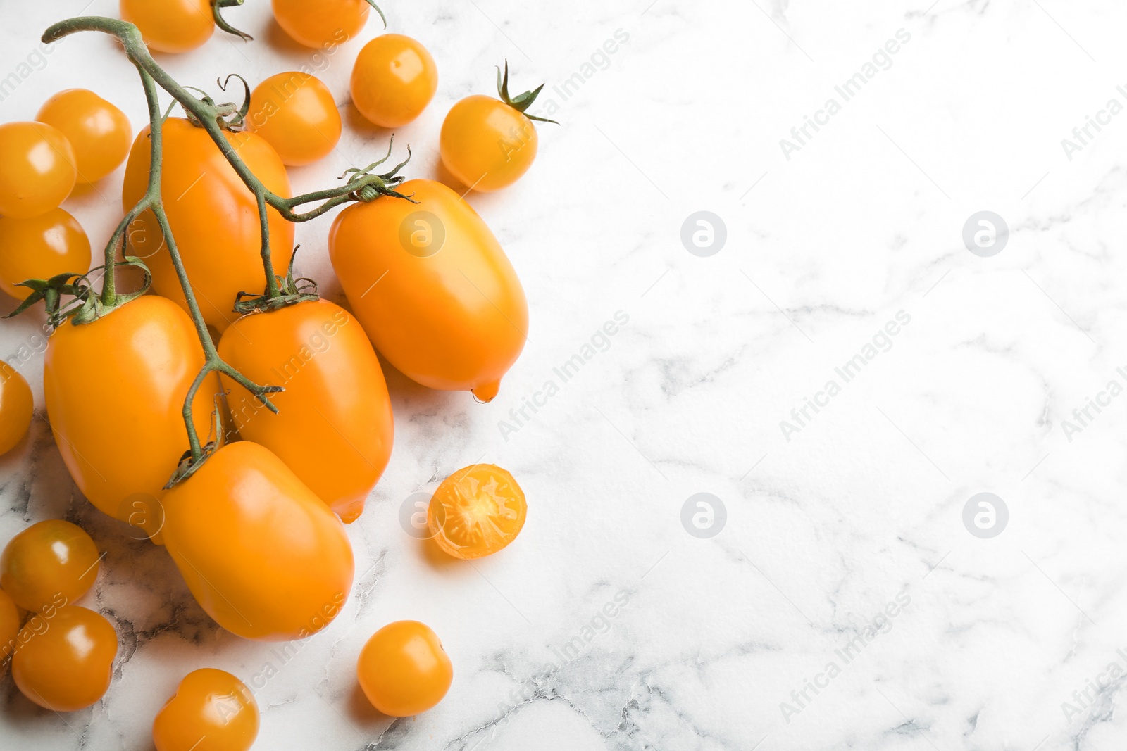 Photo of Ripe yellow tomatoes on white marble table, flat lay. Space for text