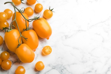 Photo of Ripe yellow tomatoes on white marble table, flat lay. Space for text