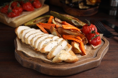 Photo of Tasty cooked chicken fillet and vegetables served on wooden table. Healthy meals from air fryer
