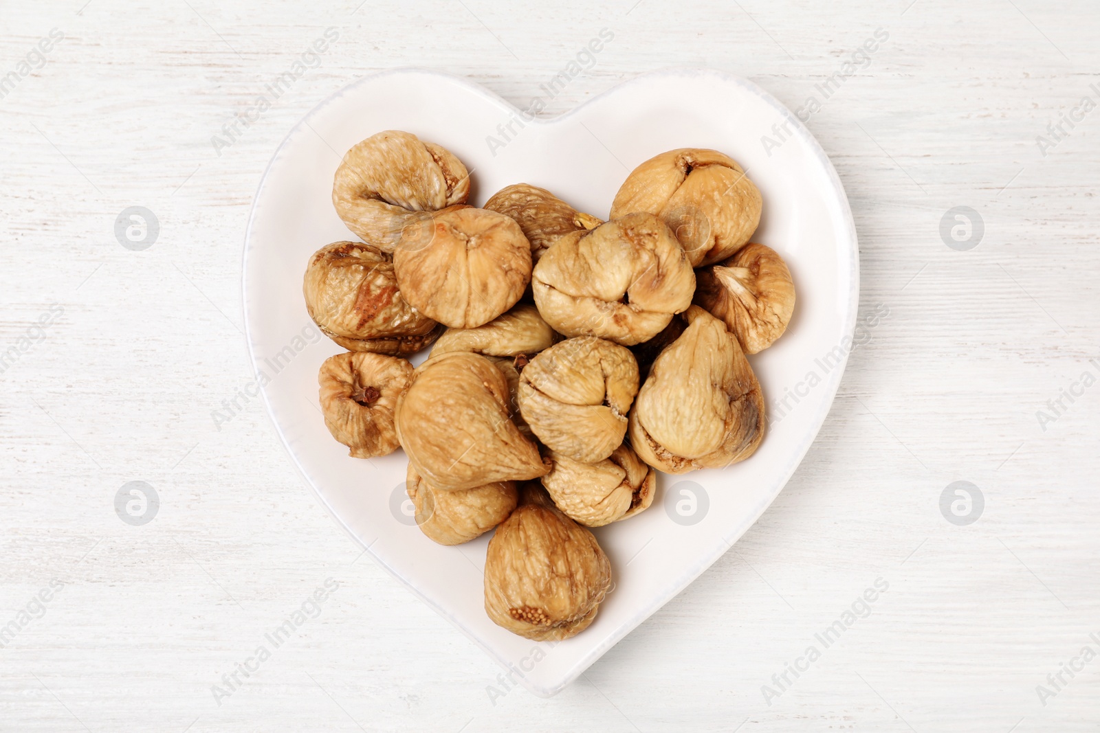 Photo of Plate with dried figs on white wooden table, top view. Healthy fruit