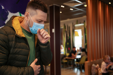 Man with disposable mask in cafe. Virus protection