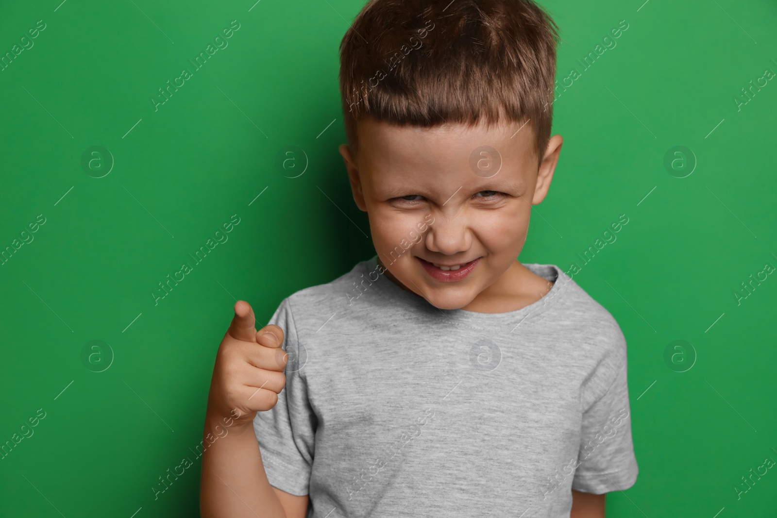 Photo of Angry little boy on green background. Aggressive behavior