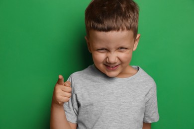Photo of Angry little boy on green background. Aggressive behavior