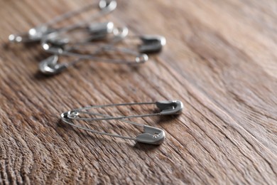 Many safety pins on wooden table, closeup. Space for text