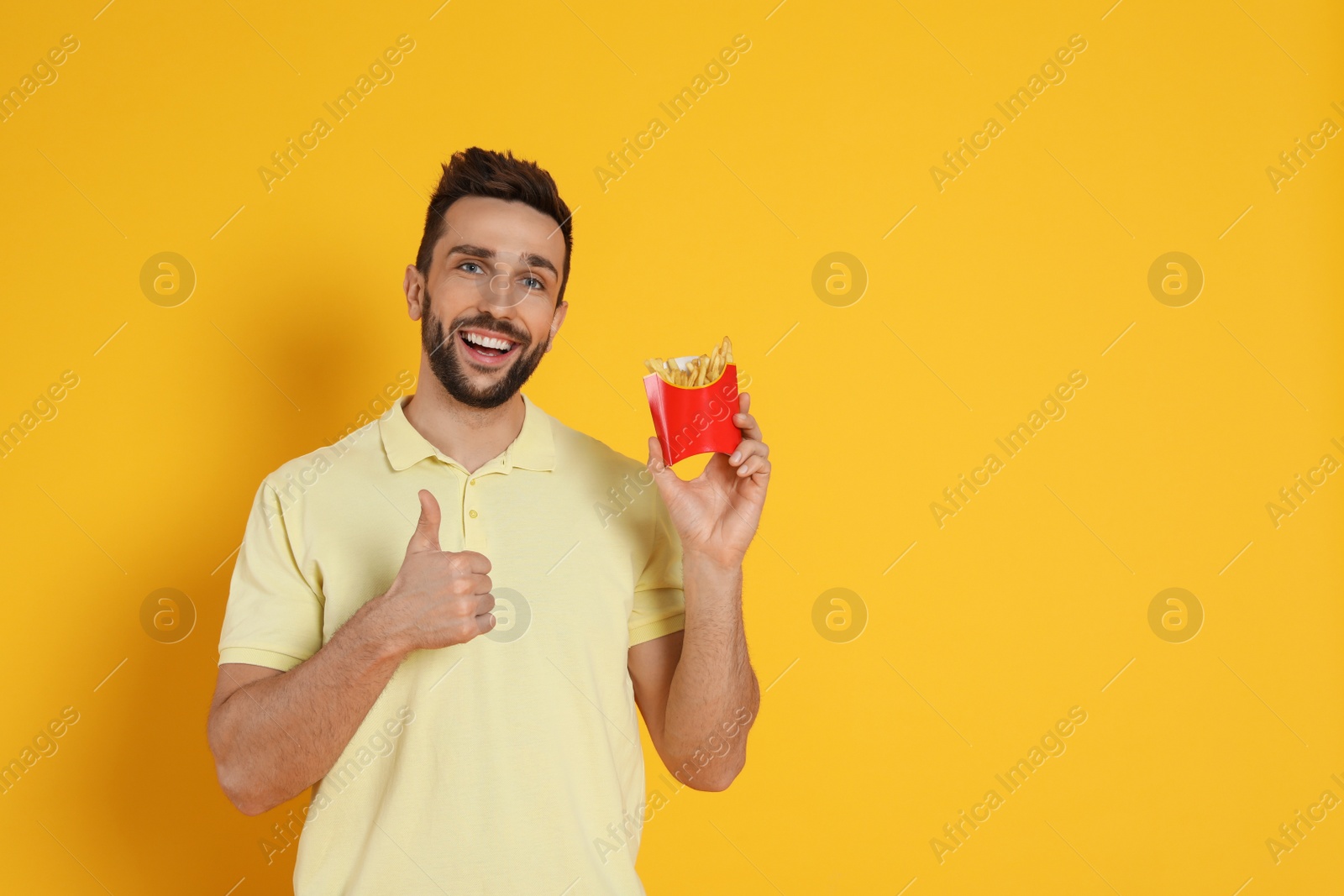 Photo of Man with French fries on yellow background, space for text