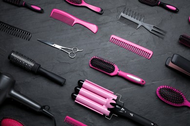 Flat lay composition of professional hairdresser tools on dark grey table