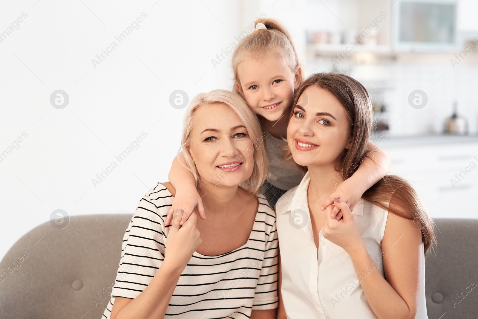 Photo of Portrait of young woman, her mature mother and daughter on sofa in living room