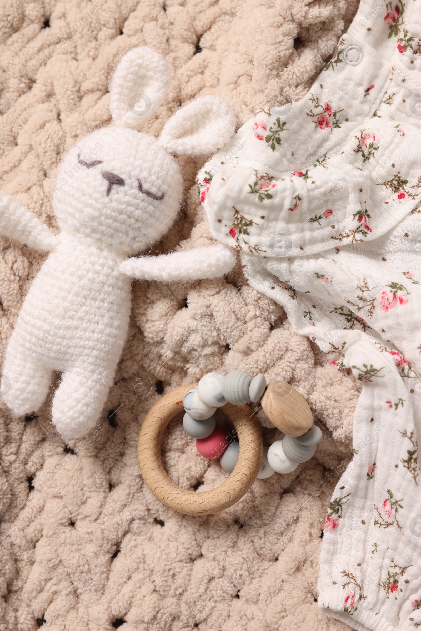 Photo of Baby accessories. Toys and cloth on knitted fabric, flat lay