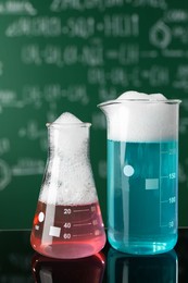 Photo of Laboratory glassware with colorful liquids on glass table. Chemical reaction