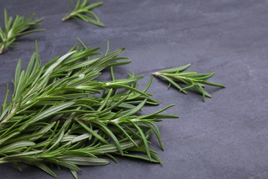 Photo of Sprigs of fresh rosemary on black table, closeup