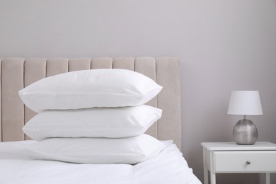 Photo of White soft pillows on bed and lamp in room