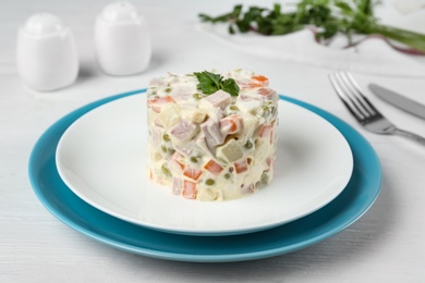 Traditional russian salad Olivier served on white wooden table