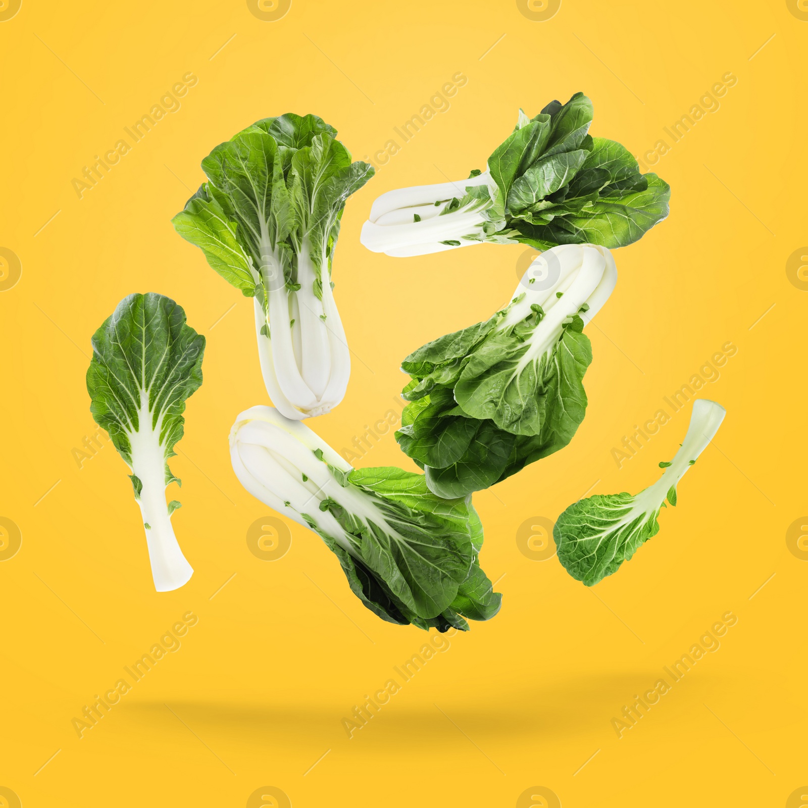 Image of Fresh green pak choy cabbages falling on yellow background