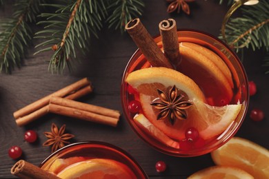 Photo of Delicious punch drink with cranberries, orange and spices on wooden table, flat lay