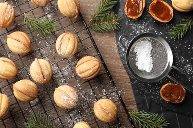 Photo of Homemade walnut shaped cookies with boiled condensed milk and fir branches on wooden table, flat lay