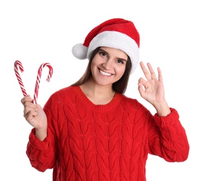 Pretty woman in Santa hat and red sweater holding candy canes on white background