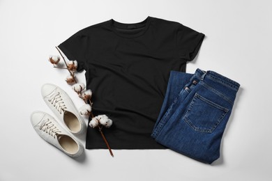 Photo of Stylish t-shirt, jeans and sneakers on white background, flat lay