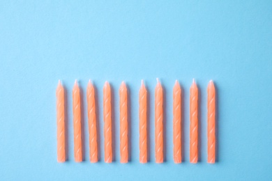 Photo of Orange birthday candles on light blue background, top view with space for text