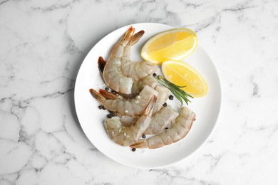Photo of Fresh raw shrimps with lemon and rosemary on marble table, top view
