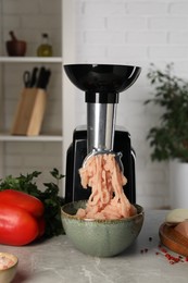 Electric meat grinder with chicken mince and products on grey marble table indoors