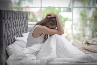 Photo of Depressed young woman in bed at home