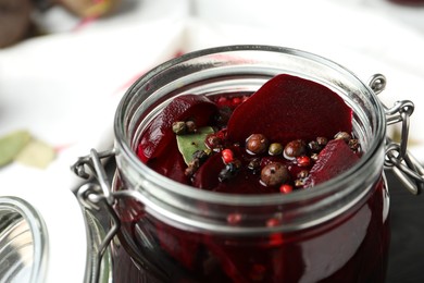 Photo of Pickled beets in glass preserving jar on table, closeup