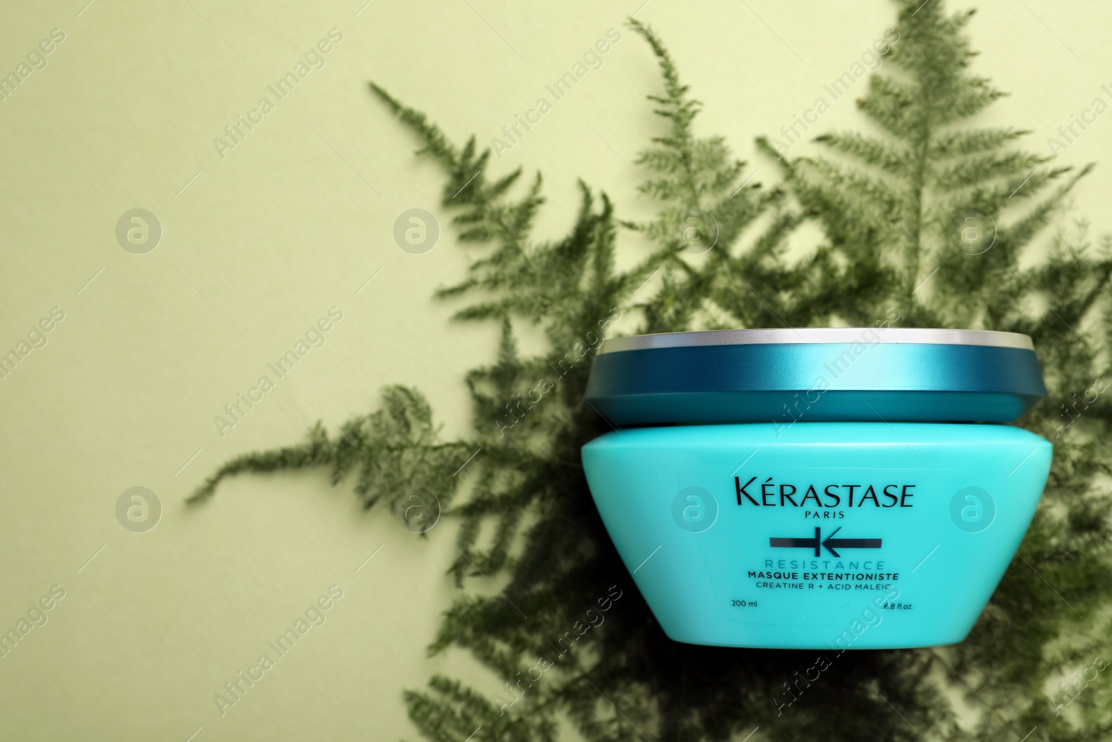 Photo of MYKOLAIV, UKRAINE - SEPTEMBER 07, 2021: Kerastase hair care mask and fern leaves on light green background, top view. Space for text