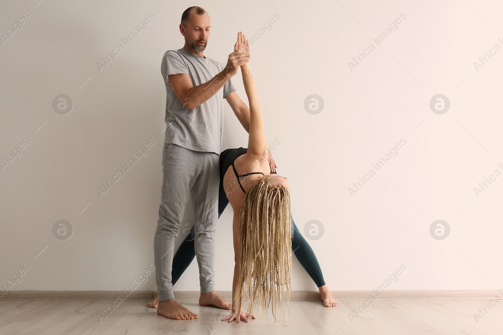 Photo of Young woman practicing yoga with instructor indoors