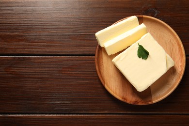 Photo of Cut tasty butter on wooden table, top view. Space for text